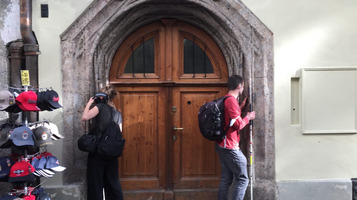 Pawel und Hemma stehen rechts und links beim Flüsterbogen in der Innsbrucker Altstadt und flüstern und hören.